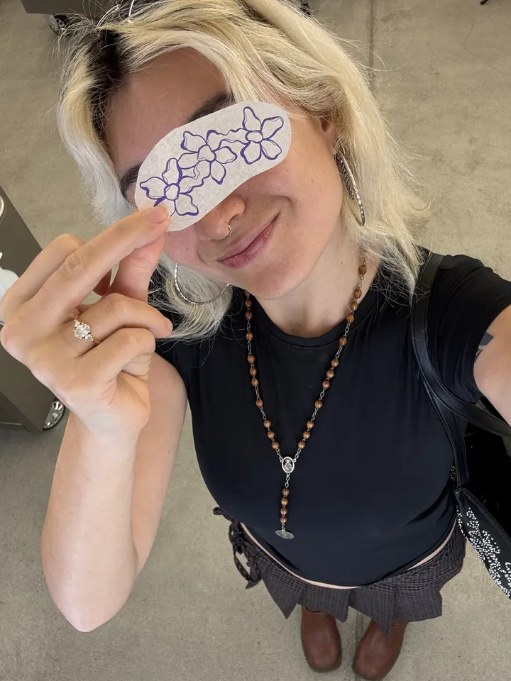Sarah at the studio, holding a cut-out blossom stencil up to her face
