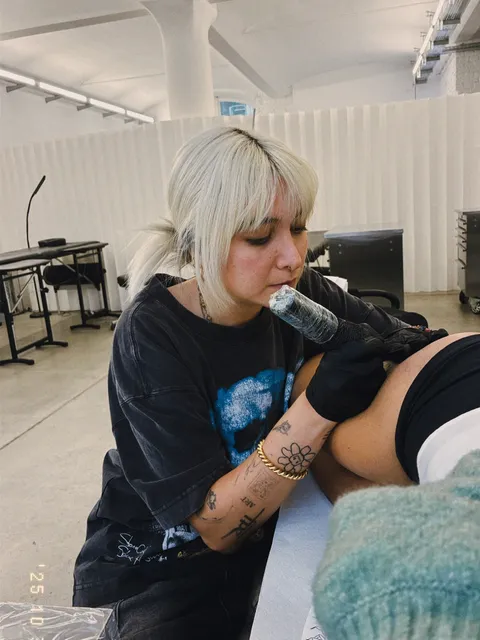 Sarah, tattoo artist in Berlin, tattooing a client