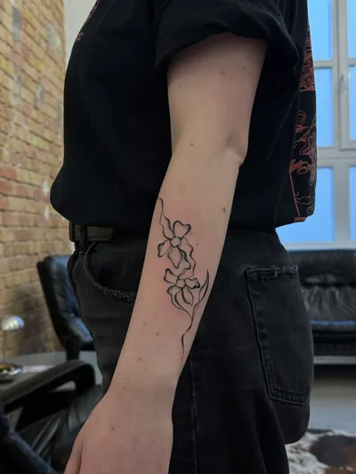 Fine-line blossoms running down the outside of a forearm