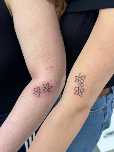 Matching fine-line blossom clusters on two arms, at the elbow and forearm