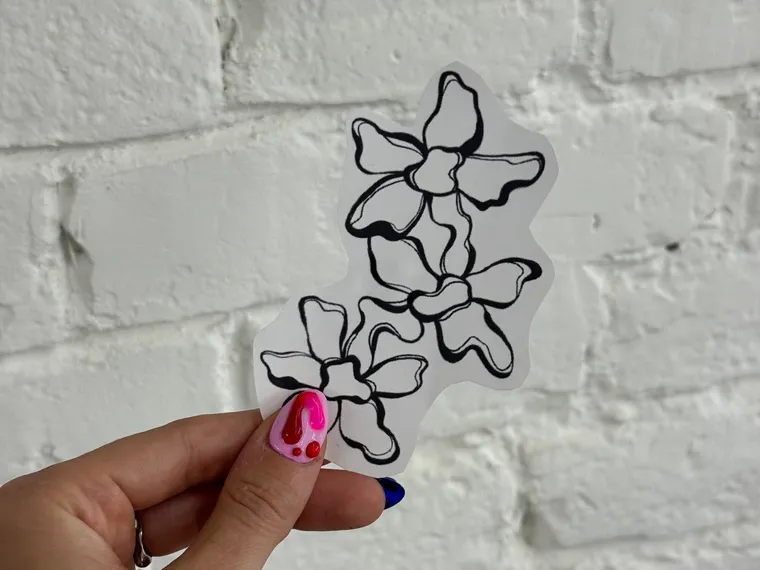 A cut-out blossom stencil held up against the studio wall before it goes on
